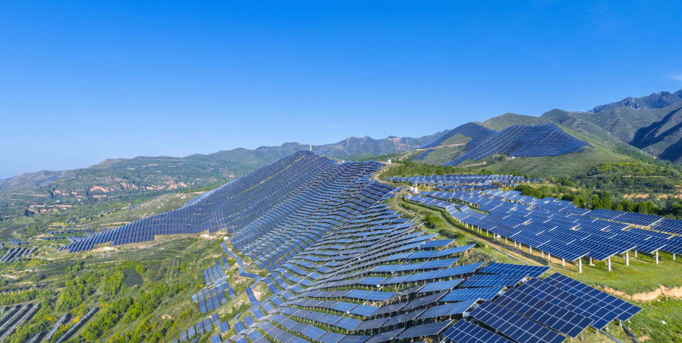 Green hillsides covered with thousands of solar panels.